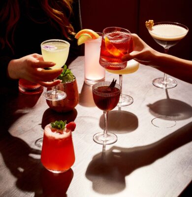 Guests enjoying a variety of colourful cocktails at a stylish hotel bar with cosy seating and elegant ambience.
