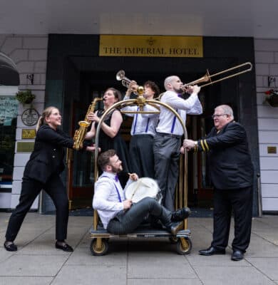 Jazz band performs joyfully at Imperial Hotel entrance, showcasing vibrant atmosphere and elegant charm.