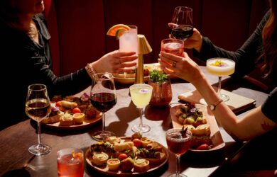 Guests enjoying gourmet appetisers and cocktails in an elegant hotel lounge with ambient lighting and plush seating.