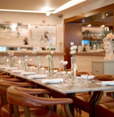 Elegant hotel dining room with marble table, plush leather chairs, and fresh flowers, offering a cosy and refined atmosphere.