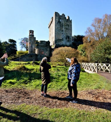 Guests enjoy exploring the historic castle grounds, capturing photos and admiring lush greenery and ancient stonework.