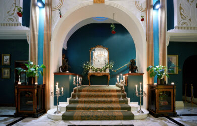 Elegant hotel lobby with grand staircase, ambient lighting, lush plants, and classic decor, creating a warm, welcoming ambience.