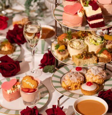 Elegant afternoon tea with scones, cakes, and tea on a rose-adorned table at a luxury hotel.