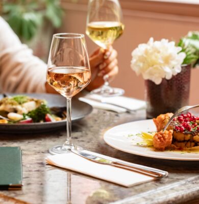Guests enjoying elegantly plated dishes with wine in a cosy hotel restaurant adorned with fresh flowers.
