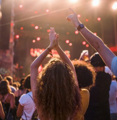 Guests enjoying vibrant outdoor festival, surrounded by lively crowd, bright lights, and upbeat atmosphere at the hotel event.