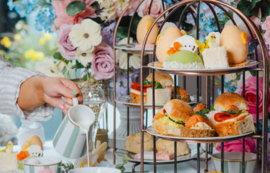 Elegant afternoon tea with tiered savouries, pastel flowers, and fine china in a luxurious hotel setting.