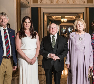 Guests stand in the elegant hotel lobby with marble floors, floral décor, and ornate chandeliers, showcasing luxury and style.