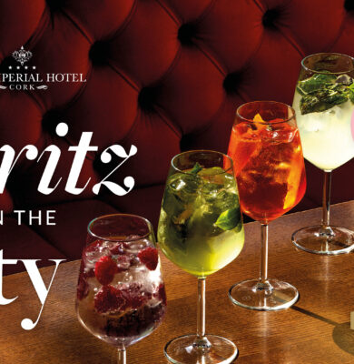 Colourful cocktails on a polished wood table at The Imperial Hotel, inviting atmosphere with plush red seating.