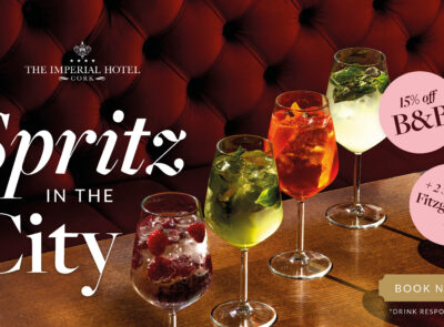 Colourful cocktails on a polished wood table at The Imperial Hotel, inviting atmosphere with plush red seating.