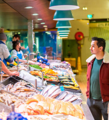 Guests exploring vibrant market with fresh seafood and local produce near boutique hotel.
